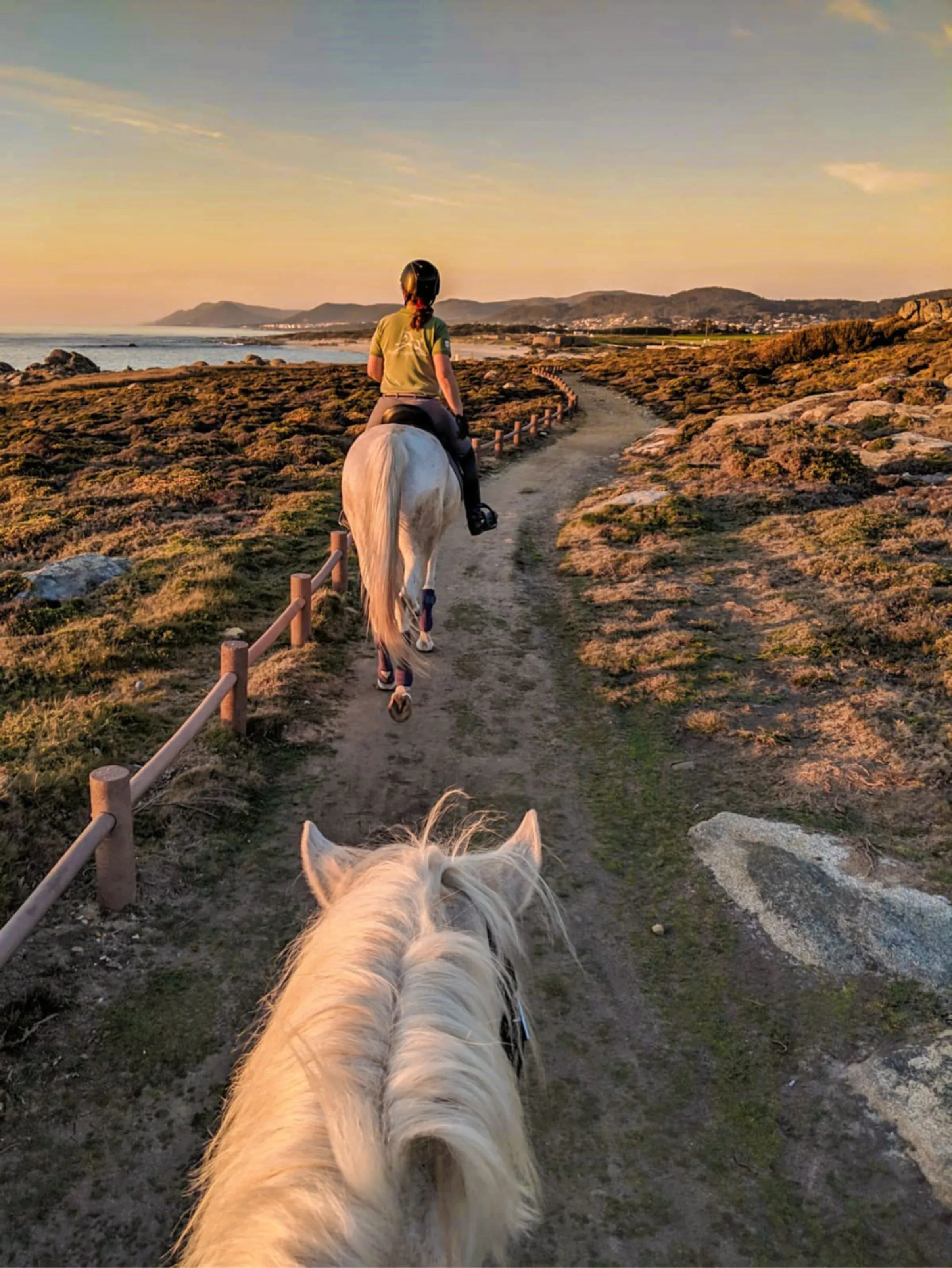 Passeio a cavalo num trilho costeiro ao pôr do sol, visto de cima do cavalo